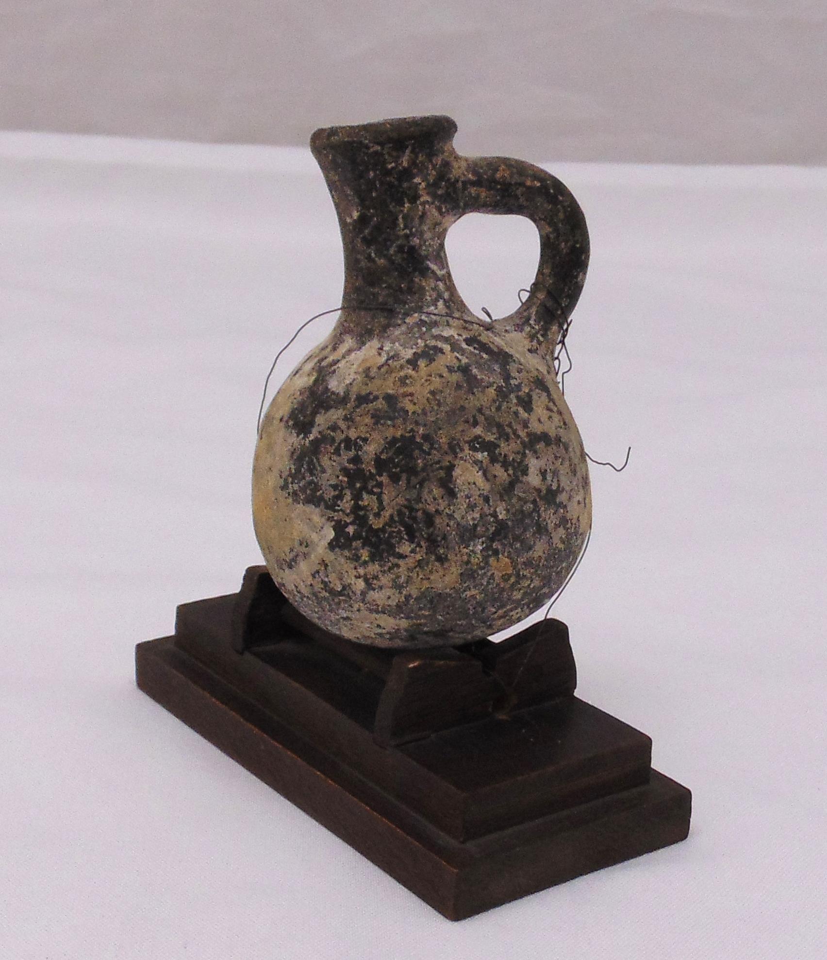 A Roman miniature ewer mounted on a rectangular plinth, 10 cm (h)