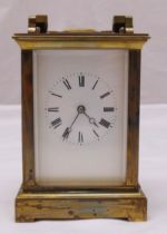 A brass chiming carriage clock, white enamel dial with Roman numerals and with swing handle
