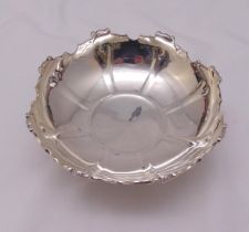 A hallmarked silver bowl of circular panelled form with applied mask and scroll border on four