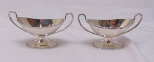 A pair of hallmarked silver oval salts with loop handles on raised oval bases, approx total weight
