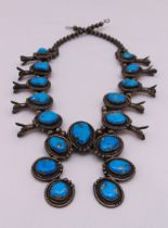 A Mexican white metal squash blossom twin bead necklace set with seventeen turquoises on shields,