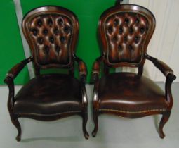 A pair of mahogany armchairs with faux leather seats and back