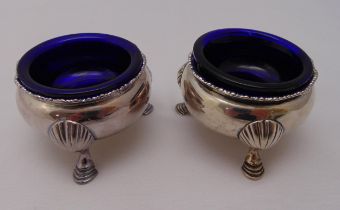 A pair of George II hallmarked silver salts with blue glass liners on three stepped hoof feet,