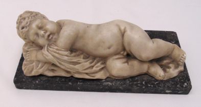 A figurine of a recumbent sleeping child on rectangular marble plinth, 9.5x 26.5 x 12cm