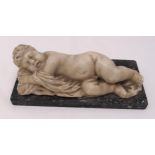 A figurine of a recumbent sleeping child on rectangular marble plinth, 9.5x 26.5 x 12cm