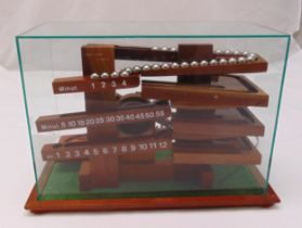 A wooden Rolling Ball mantle clock in fitted glass case to include 30 metal balls