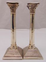 A pair of hallmarked silver Corinthian column table candlesticks on stepped square bases with beaded