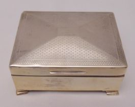 A rectangular hallmarked silver cigarette box with hinged engine turned cover on four bracket feet