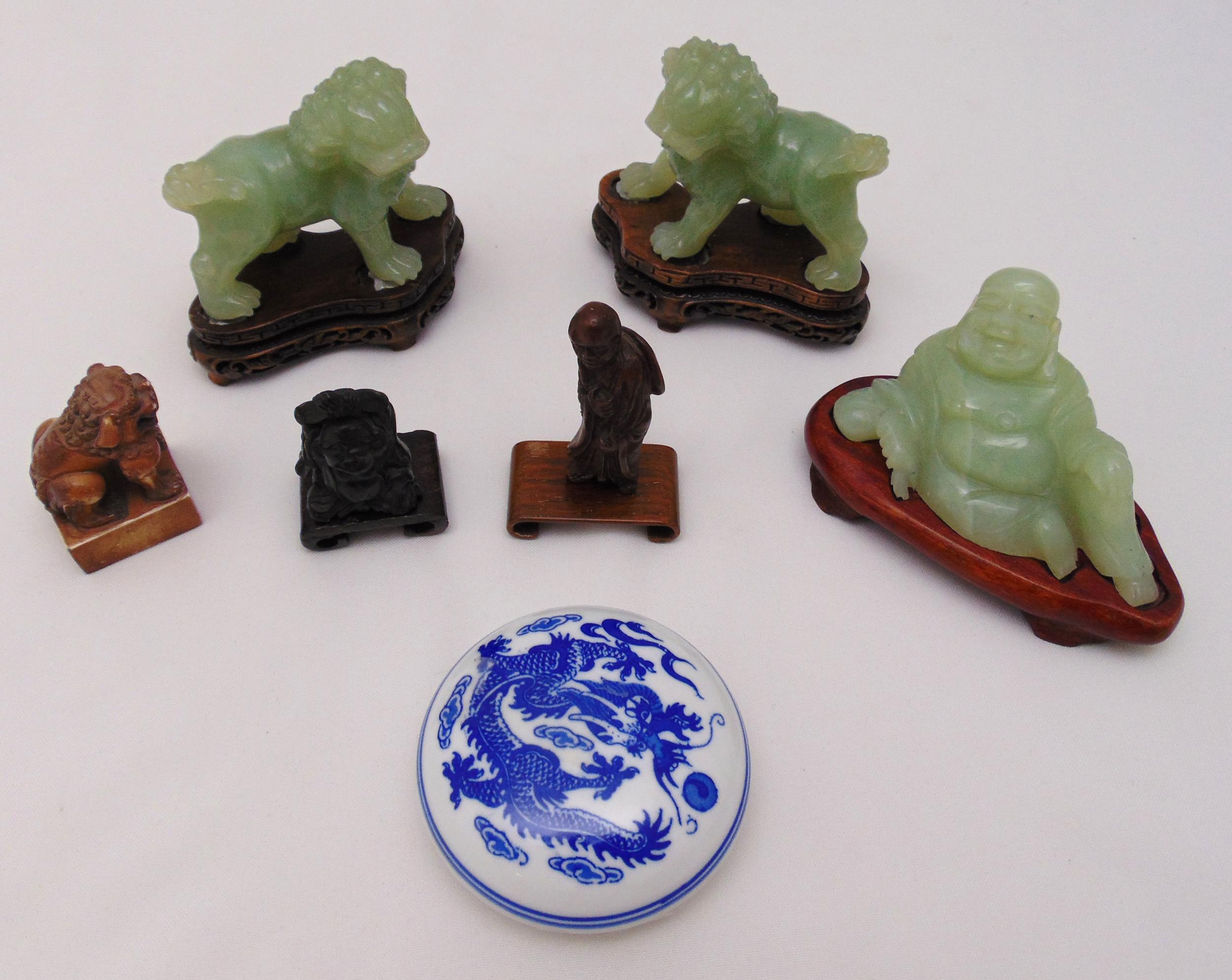 A pair of jadeite dogs of foe on carved wooden stands, a jadeite figurine of a reclining Buddha on a