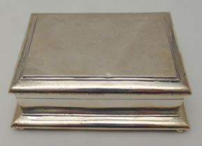 A rectangular hallmarked silver cigarette box with hinged cover on four bun feet