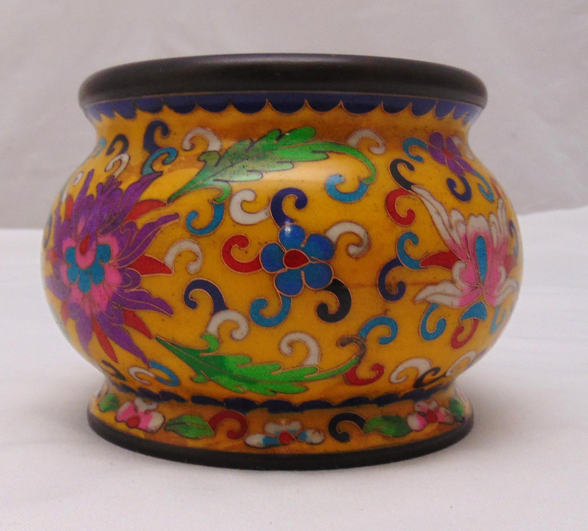 A Chinese bronze and cloisonn‚ incense burner decorated with flowers and leaves against a yellow