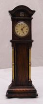 An Edwardian miniature oak cased grandfather clock with flanking brass columns on raised rectangular