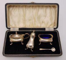 A hallmarked silver cased three piece condiment set to include one condiment spoon