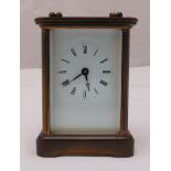 A brass carriage clock of customary form, white enamel dial with Roman numerals and carrying handle,