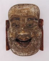 An oriental carved painted wooden mask in the form of a laughing man, 9.5 x 24.5 x 29.5cm