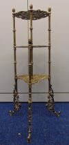 A three tier brass whatnot the scroll and leaf pierced shelves embossed with birds and foliage all