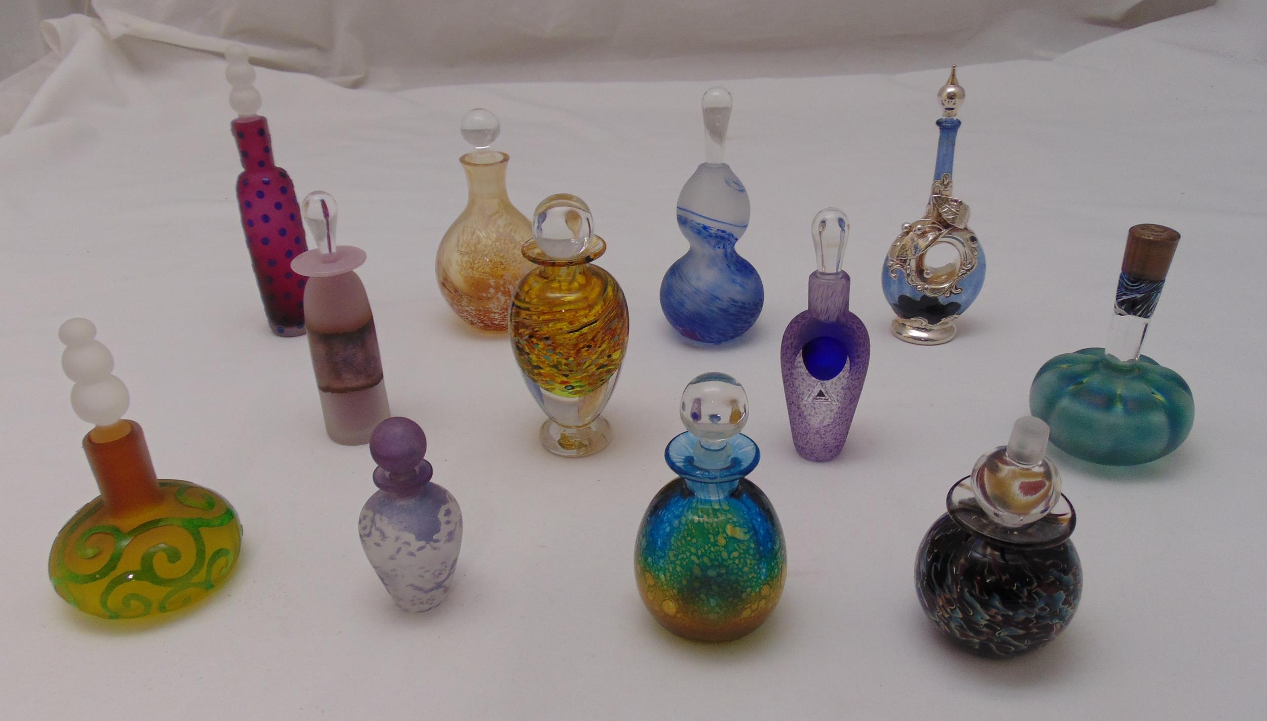 Twelve coloured glass dressing table perfume bottles of various form, size and colour