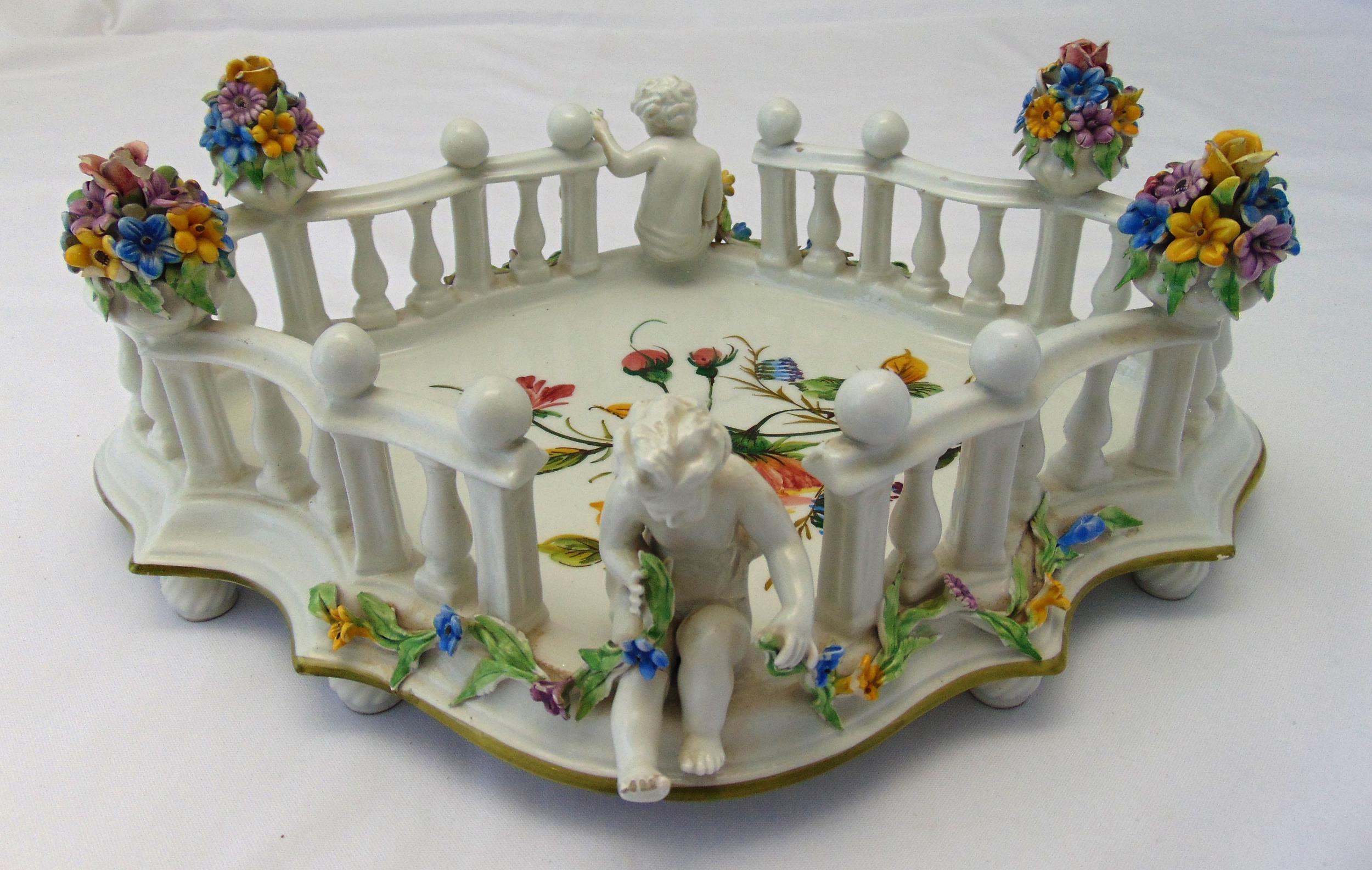A Dresden shaped rectangular table centre piece, decorated with applied putti and floral sprays,
