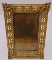 A rectangular brass photograph frame, scroll pierced sides set with rosettes with hinged back strut,