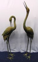 A pair of patinated bronze figurines of standing cranes in the Japanese style, one with upheld