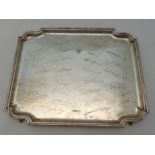 A hallmarked silver shaped rectangular presentation tray on four bracket feet with facsimile