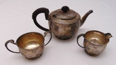 A hallmarked silver Art Deco three piece teaset, cylindrical form with scroll handles on raised