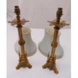 A pair of Gothic style brass table candlesticks on triform bases, converted to electric, to