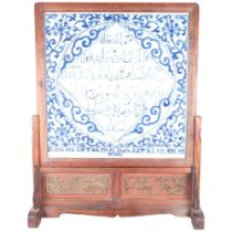 A large middle eastern blue and white ceramic tile, with a scripted cartouche, mounted in a hardwood