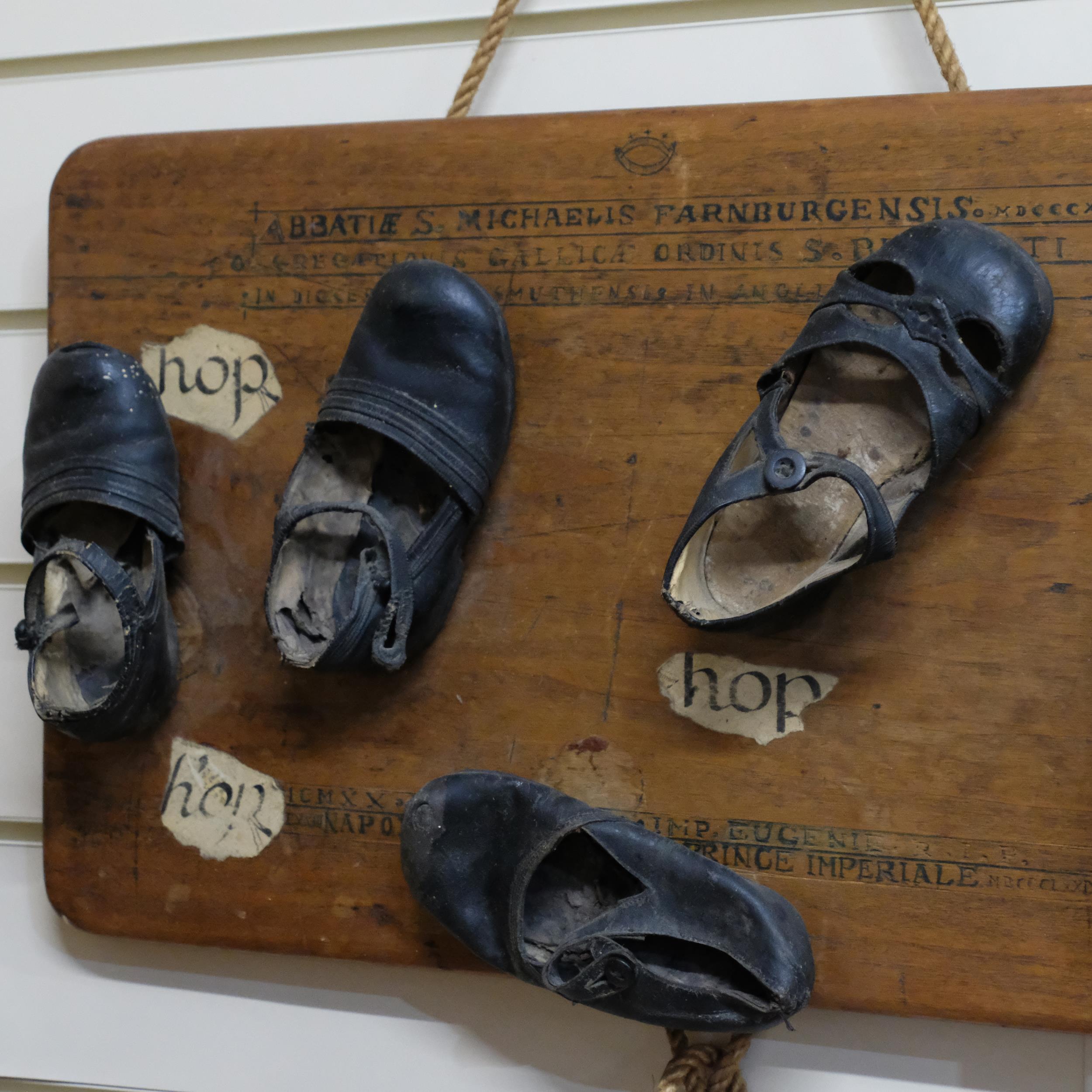 A folk art sculpture - group of 5 antique children's shoes, mounted on board, with roman script. W - - Image 2 of 2