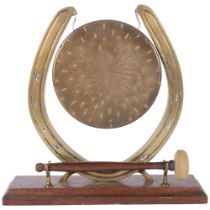 A brass gong in horseshoe design stand, on oak plinth, with striker, H27cm