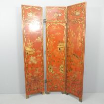 A Japanese red lacquered three-fold room divider screen, with gilded and painted decoration. Each