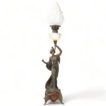 An Art Nouveau oil lamp, supported by a bronze patinated spelter figure of a woman, lustre glass