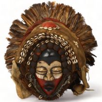 A large Dan, Ivory Coast headdress, with feather and shell decoration, height approx 56cm