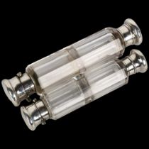 A graduated pair of glass double-ended travelling scent bottles, unmarked white metal mounts,