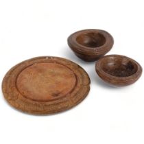 An early 20th century carved wood bread board, diameter 29cm, and 2 Antique turned wood bowls,