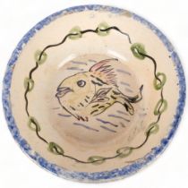 An early 20th century large French glazed terracotta bowl, with sponged and painted fish decoration,