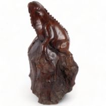 A large carved hardwood study of a iguana climbing a tree stump, H56cm