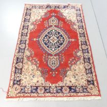A red-ground Persian rug. 180x119cm. Repair visible to one corner. Some small areas of damage