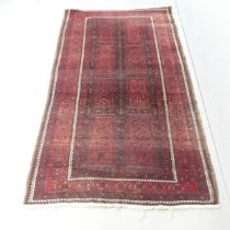 A red-ground Persian rug. 228x125cm. Some loss to fringes, moth damage and marks and stains. Would