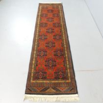 A red-ground Afghan design runner. 250x64cm.