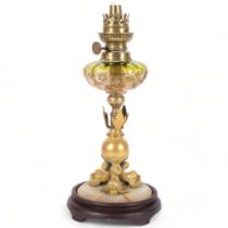 A small gilt-metal oil lamp on an onyx and turned wood base, with an engraved green glass font,