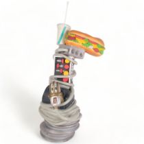 A composite sculpture, an animated microphone wrapped around various electrical equipment,
