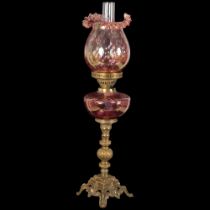 An Antique Duplex glass and brass oil lamp, with a frilled red glass shade and matching font,