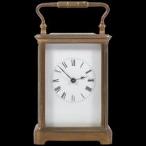 An Antique brass-cased carriage clock with striking movement, white enamel dial and carrying handle,