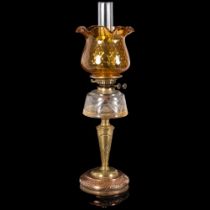 An Art Nouveau copper and brass oil lamp, with an amber frilled edge shade, and clear glass font,