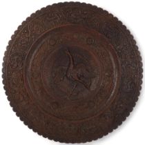 A large 19th century ornate carved teak panel of circular form, with a central bird design, diameter