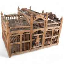 A large palace design wooden hanging bird cage, with figural guard to front door, 76cm x 51cm x 49cm