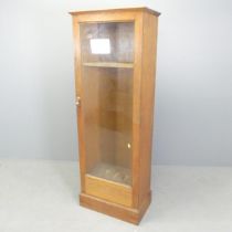 An oak gun cabinet with single glazed door. 55x154x33cm. Drawer to base fitted with campaign style