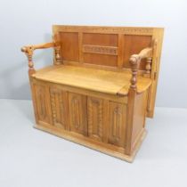 An early 20th century oak monk's bench, with lifting seat and applied carved and panelled