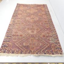 A red-ground Meshwani carpet. 245x142cm. Some repairs visible. Some holes and moth damage visible.